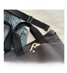 Detail der schwarzen Nylon-Tragetasche mit Druckknopftasche vorne und verstellbarem Gurt