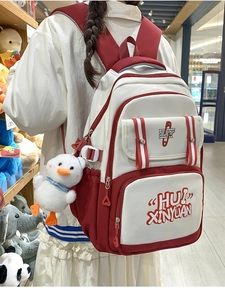 Detail view of red and white canvas backpack with a cute white duck plush keychain