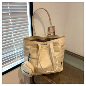Detail view of the cream canvas tote bag showing the matching round coin purse and logo
