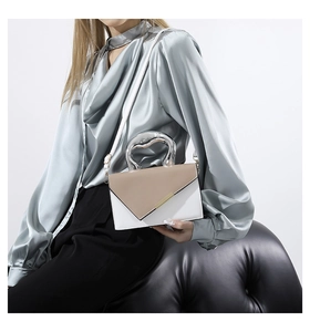 Detail of a contrast color square bag with unique silver metallic handle and shoulder strap