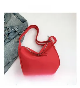 Vue détaillée du sac croissant en nylon rouge avec bandoulière et mini pochette ronde