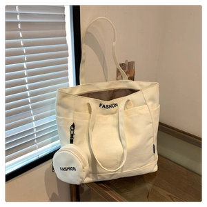 Detail view of cream canvas tote bag with fashion print and mini round coin purse charm