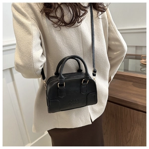 Detail of black matte leather Boston bag with embossed logo and golden metal hardware