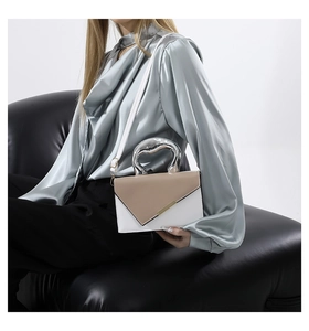 Detail of elegant two-tone beige handbag featuring a silver heart-shaped metal handle