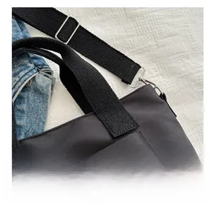 Detail der schwarzen Nylon-Tasche mit breitem Webgurt und silberner Metallschnalle