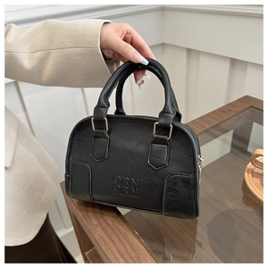 Close-up of black Boston handbag with embossed ORN letters and golden zipper details