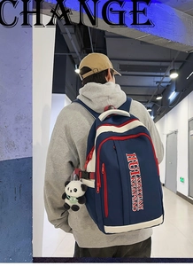 Detail of navy blue nylon backpack with red zipper trim shown on male model back