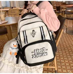 Close-up of contrast school backpack featuring a cute white duck plush keychain and pockets