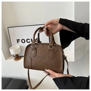 Detail shot of brown lychee texture faux leather bag with embossed logo and metal hooks
