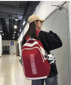 Detail of red and white nylon backpack with cute panda charm and artistic text
