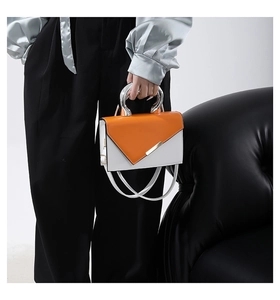 Detailed view of the orange and white contrast crossbody bag with silver metal ring handle