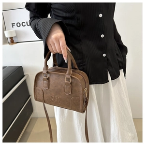 Detail of dark brown vintage Boston bag with ORN embossed letters and gold metal hardware