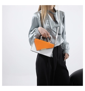 Detail view of the sleek metal handle and orange contrast flap on the white leather bag
