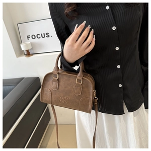 Detail of vintage brown Boston bag with embossed logo and premium gold hardware