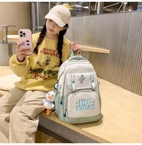 Detail of multi-pocket canvas backpack in mint green with cute duck plush pendant