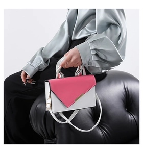 Detailed close-up of a two-tone crossbody bag with silver metallic handle and refined texture