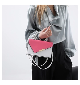 Detail of contrast square bag with U-shaped silver metal handle and gold metal fastener
