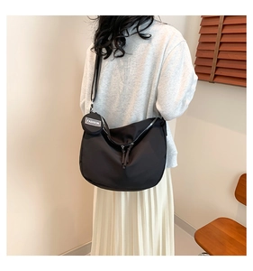 Détail d'un sac bandoulière en nylon noir avec un petit porte-monnaie rond à la mode