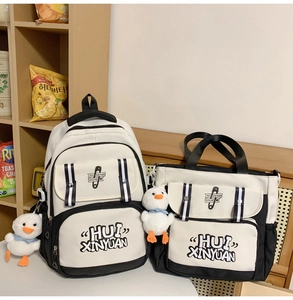 Detail view of the black and white canvas backpack set featuring cute duck plush charms