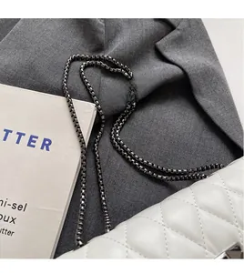 Close-up of white quilted leather bag featuring metal chain strap and rivet details