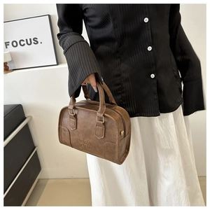 Close-up of vintage brown leather Boston handbag with embossed lettering and metallic zipper
