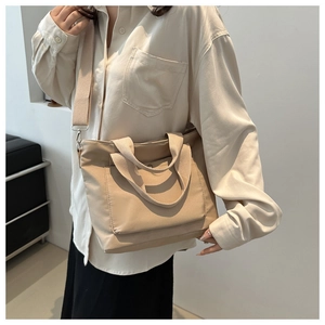Detail der minimalistischen beigen Nylontasche mit breitem Gurt und Fronttasche