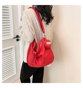 Détail d'un sac cabas en nylon rouge avec porte-monnaie assorti et bandoulière réglable
