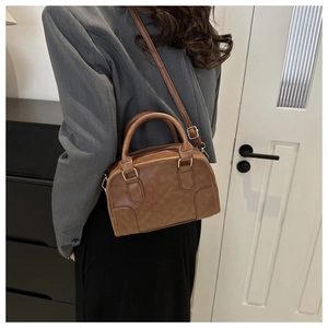 Detail of warm brown vintage Boston bag with brand embossing and gold hardware