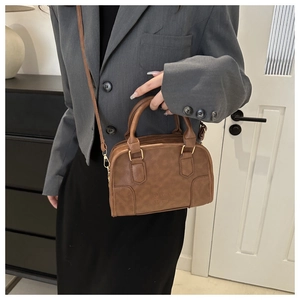 Caramel brown vintage Boston bag with gold hardware shown on a model in a grey suit