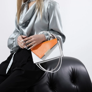 Orange and white contrast leather handbag with silver ring handle shown with a model