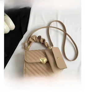 Detail view of beige quilted handbag with gold heart buckle and ruffled cloud handle