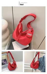 Détail d'un grand sac bandoulière rouge avec porte-monnaie rond et pampilles