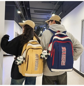 Detail of yellow and navy nylon backpacks with cute panda plush charms for students
