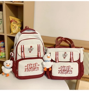 Detail of red and white canvas backpack set with HUI XINYUAN logo and cute duck charms