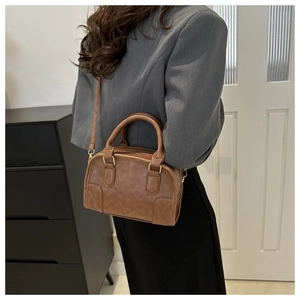 Detail of caramel brown Boston bag showing textured faux leather and gold hardware
