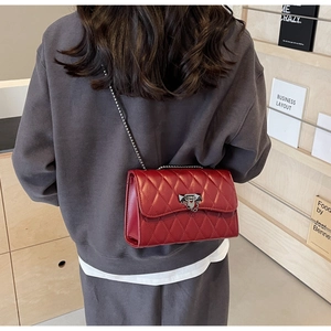 Detail view of red quilted leather crossbody bag with silver chain and metal lock