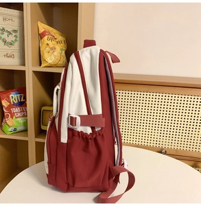 Detail view of red and white backpack with mesh straps and adjustable side buckle strap