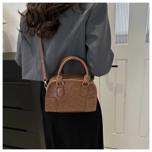 Classic retro brown Boston bag shown on model for a stylish casual look in soft lighting