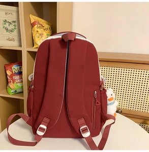 Deep red canvas backpack featuring padded straps and a secure anti-theft side zipper pocket