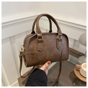 Detail view of dark brown vintage faux leather Boston bag with embossed logo and handle