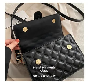 Close-up of black quilted shoulder bag with magnetic snap buckle and gold hardware detail