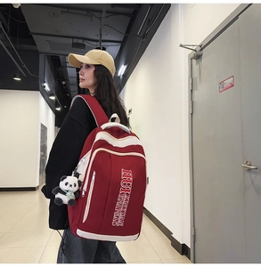Detail of red and white nylon backpack with cute panda charm and multi-layer zippers