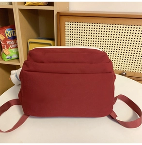 Detail view of the burgundy backpack back with multi-layer folds and durable woven straps