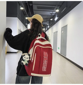 Detail view of large red nylon backpack with contrast cream trim and cute panda pendant