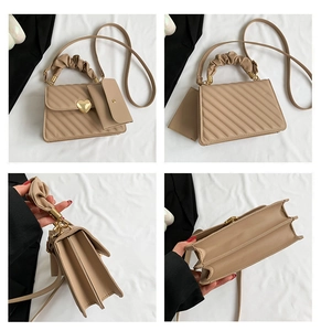 Detail view of khaki quilted small square bag featuring a gold heart clasp and pleated handle