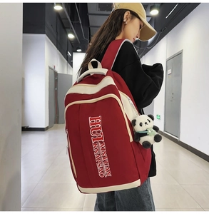 Detail view of red and beige nylon backpack with side pockets and panda plush charm