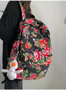 Detailed side view of ethnic floral backpack with a cute white duck plush charm pendant