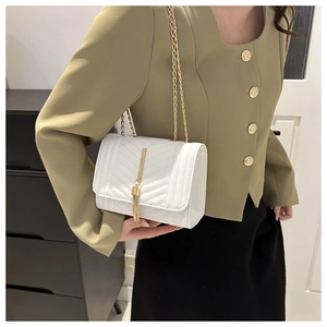 Détail du sac à main blanc matelassé avec bandoulière dorée et pompon métallique élégant