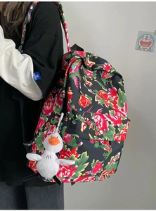 Macro detail of floral backpack featuring large red blossoms and cute plush duck pendant