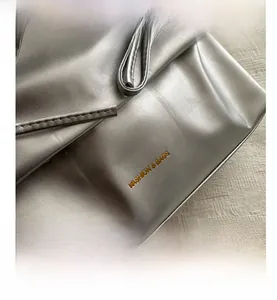 Close-up of metallic silver faux leather texture with golden FASHION & BAGS logo embossing